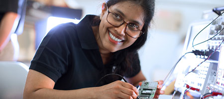 Female engineer with a bright smile uses an oscilloscope.