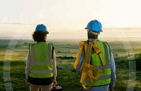 A woman and a man, both installers, standing and looking at a green landscape during sunrise.